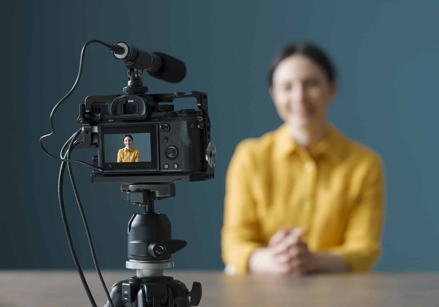 Smiling woman sitting in front of a camera and making a video blog